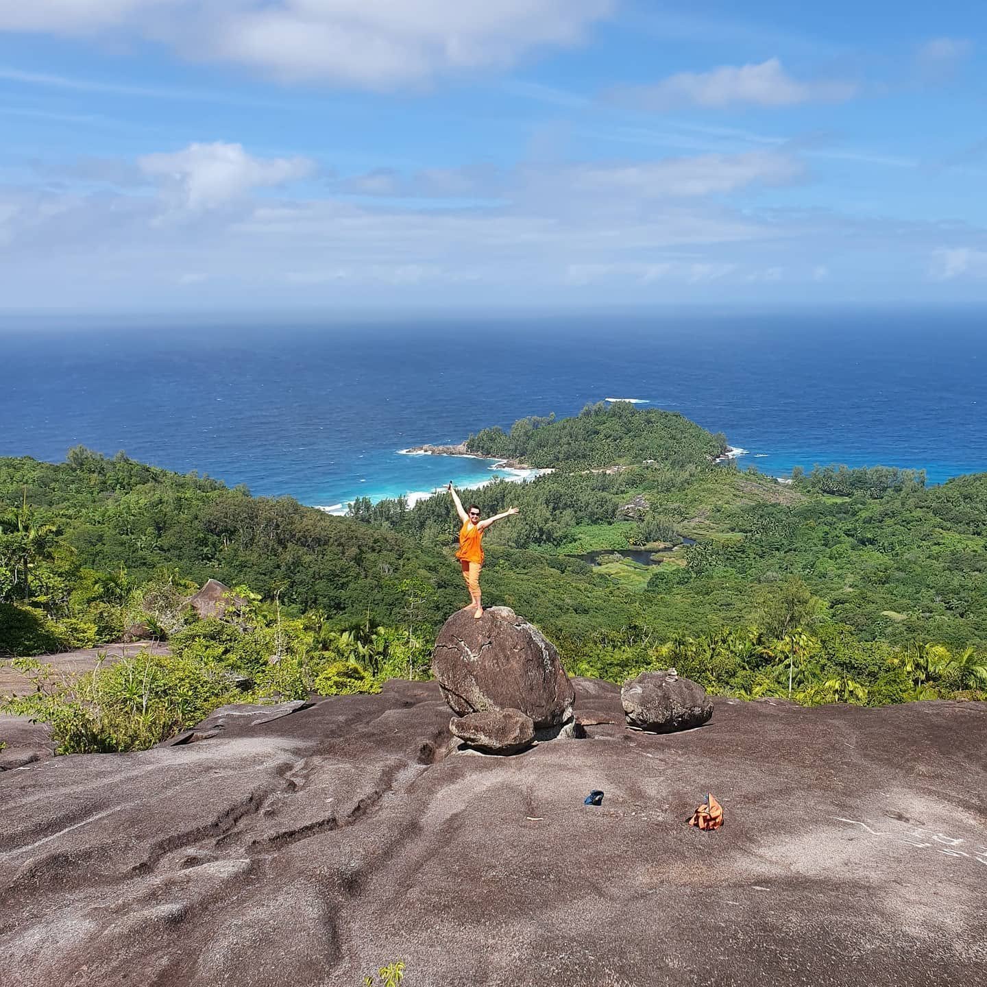 En vandrer står på klippen over Baie Lazare på Mahé og ser ud over bugten
