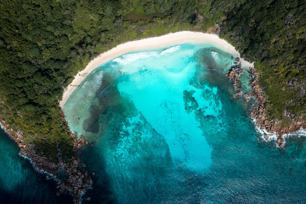 Anse Cocos på La Digue set fra luften, med lyse render i det lave vand
