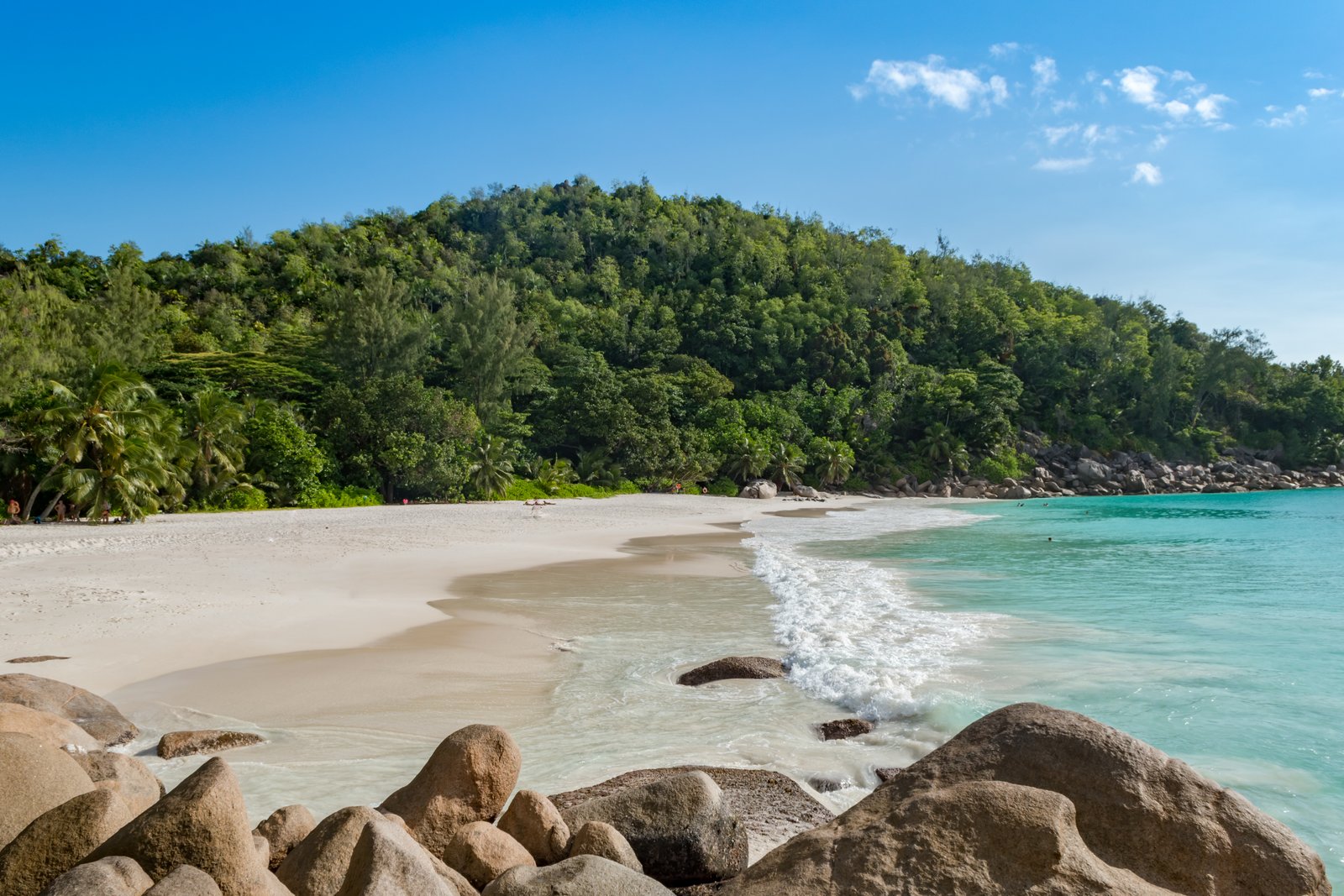 Anse Georgette på Praslin, med granitklipper i vandkanten og en grøn bakke bag stranden