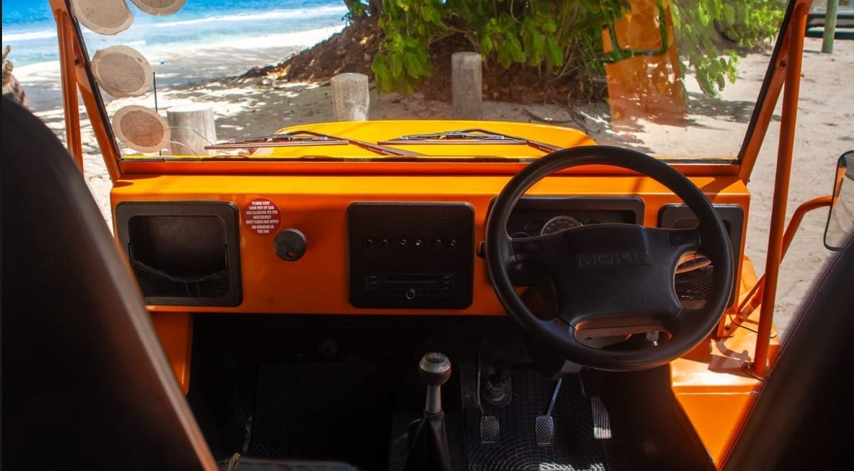 Instrumentbordet og rattet i en Mini Moke med udsigt ud over havet