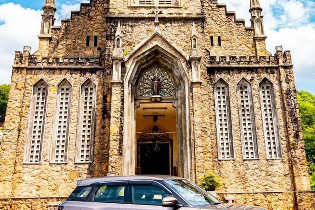 Suzuki Brezza set fra siden foran en gotisk granitkirke på Mahé
