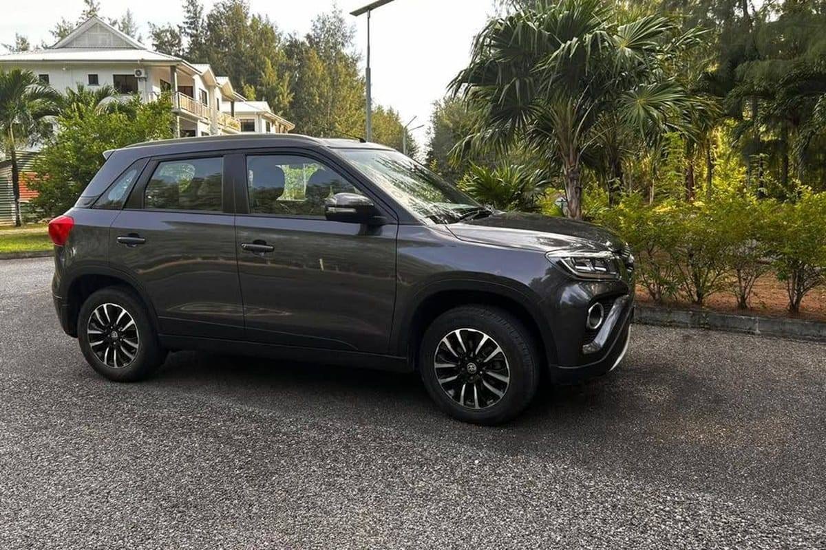 Den grå Toyota Urban Cruiser set fra siden med palmer bagved