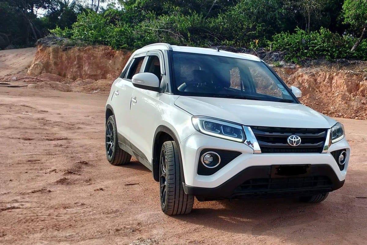 En hvid Toyota Urban Cruiser på en kystvej, set skråt forfra