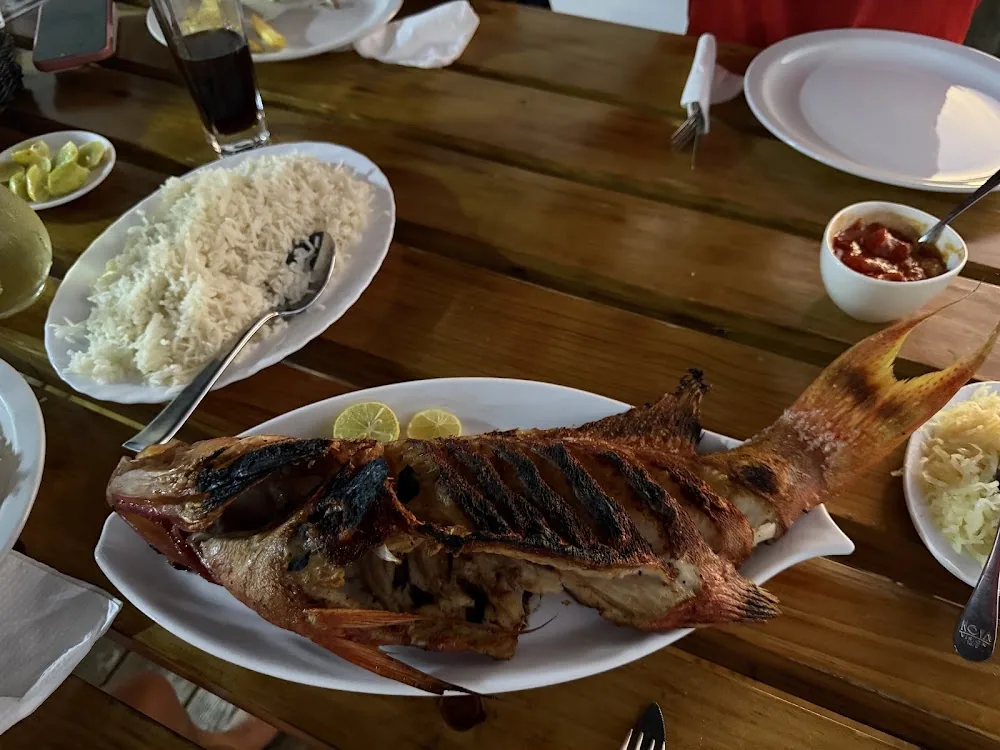Grillet fisk med ris og tilbehør på et bord på Anse Soleil Café på Mahé