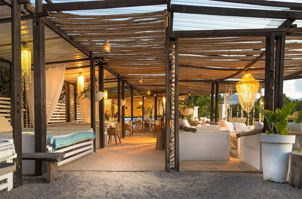 Den åbne terrasse på Bliss Hotel på Mahé, med lamper under et træloft