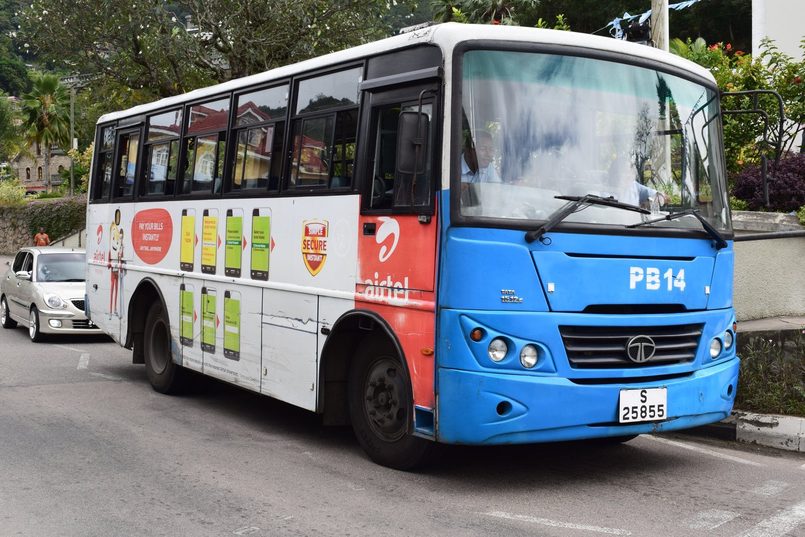 En blå og hvid Tata-bus ved kantstenen i Victoria med rutenummer på skiltet