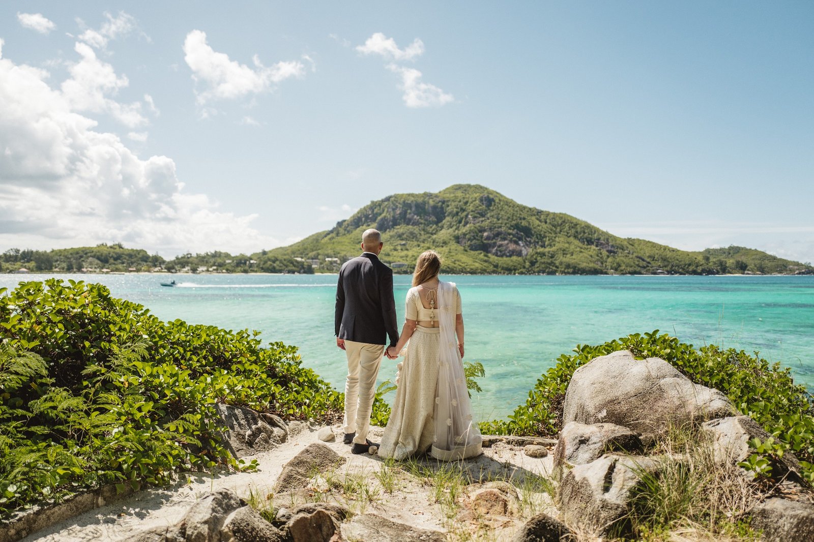 Et par på klipperne med en grøn ø bag sig ved Praslin